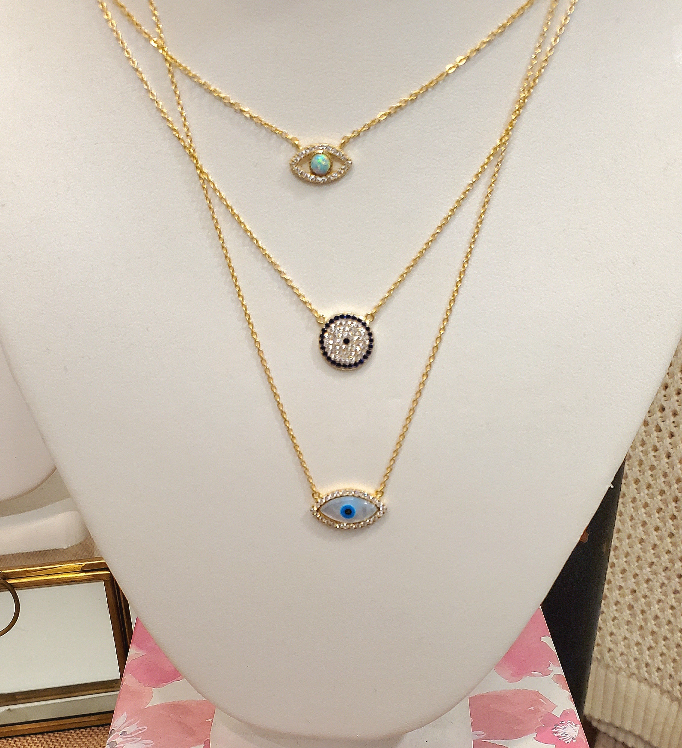 Evil Eye Mother Of Pearl and CZ stones bordering the eye shape charm on a gold chain