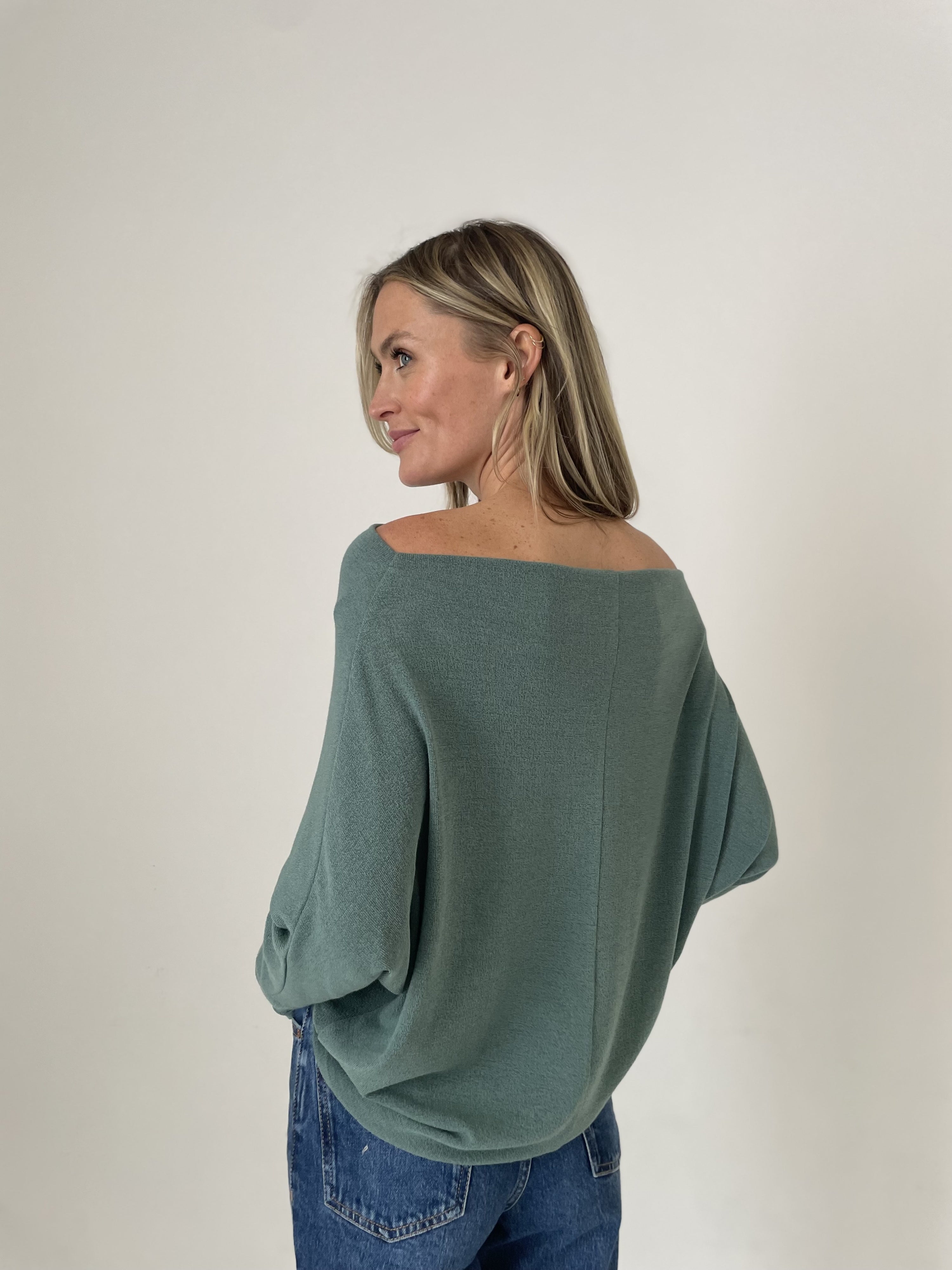 model wearing evergreen off the shoulder knit top with long sleeves.