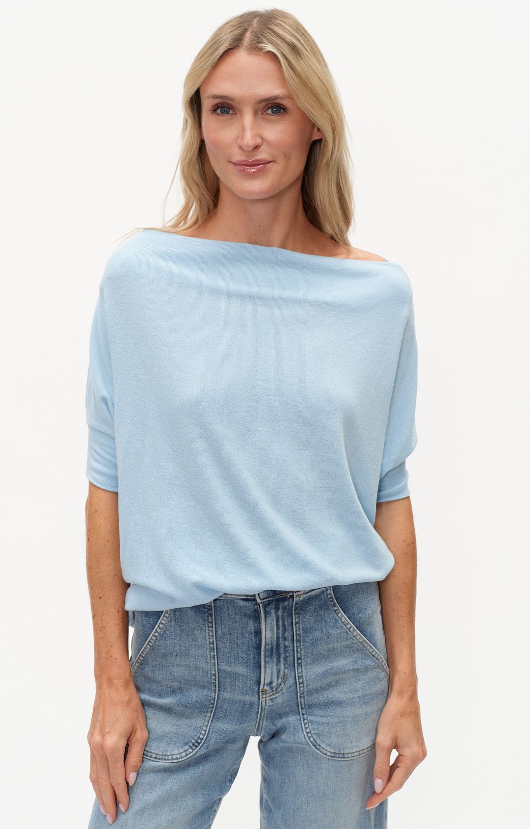 Woman wearing a light blue sweater and jeans on a white background