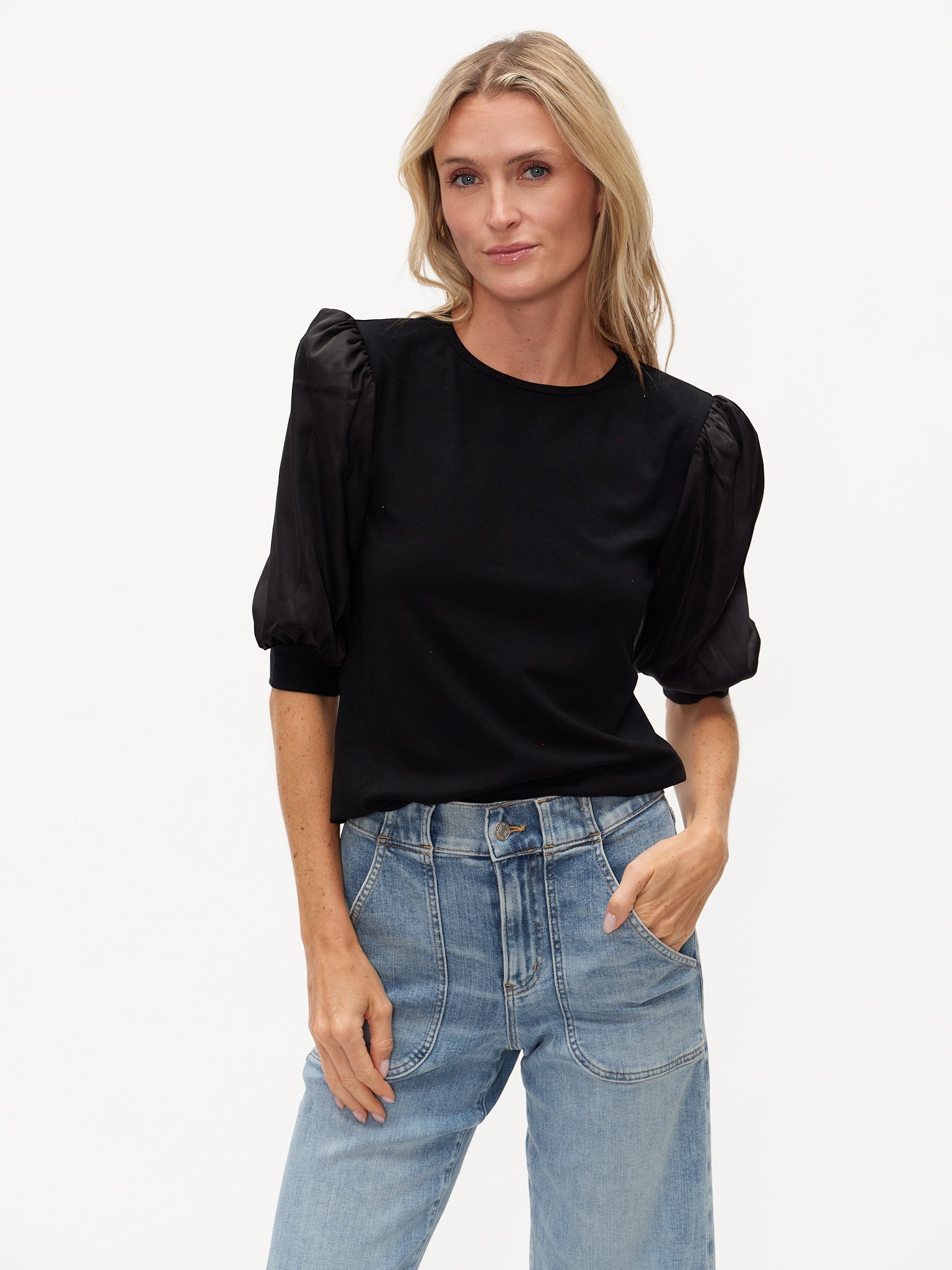 Model wearing a black knit top with short satin sleeves.