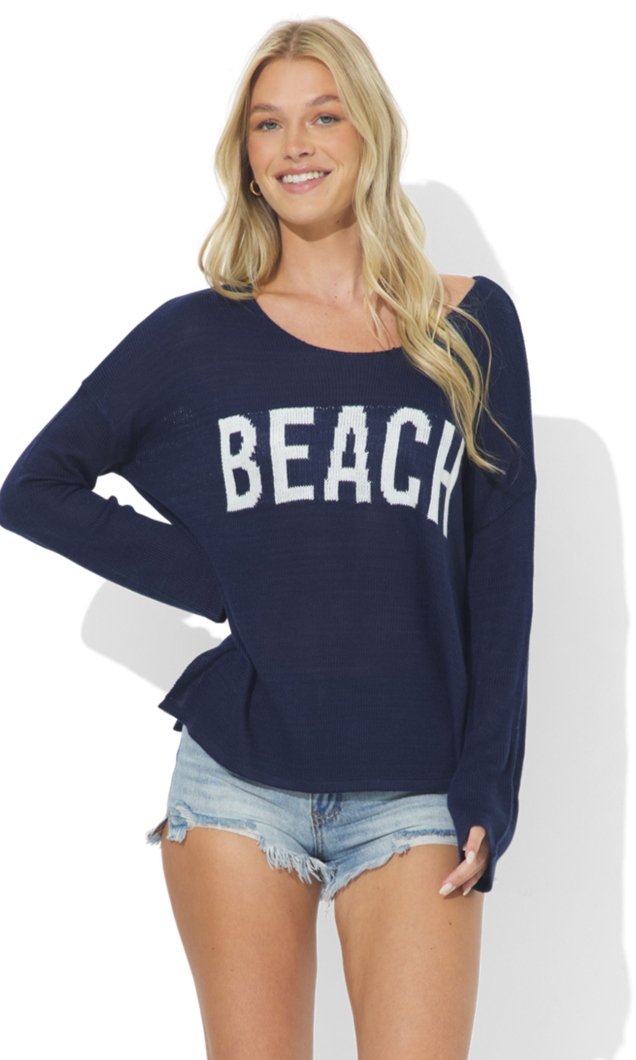 Woman wearing a navy blue sweatshirt with 'BEACH' text, standing against a white background