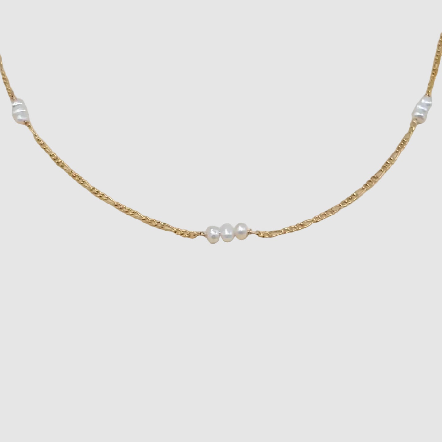 Gold chain necklace with pearls on a beige background